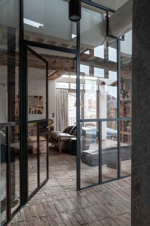 Blick durch eine gläserne Wand in ein Wohnzimmer mit Steinmauern